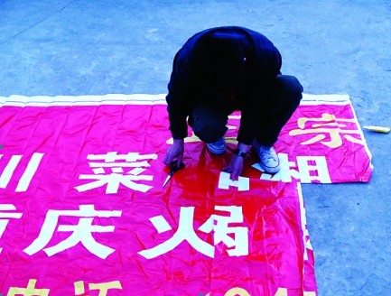 魏明辉正在从广告布上选取用于制作产品的图案